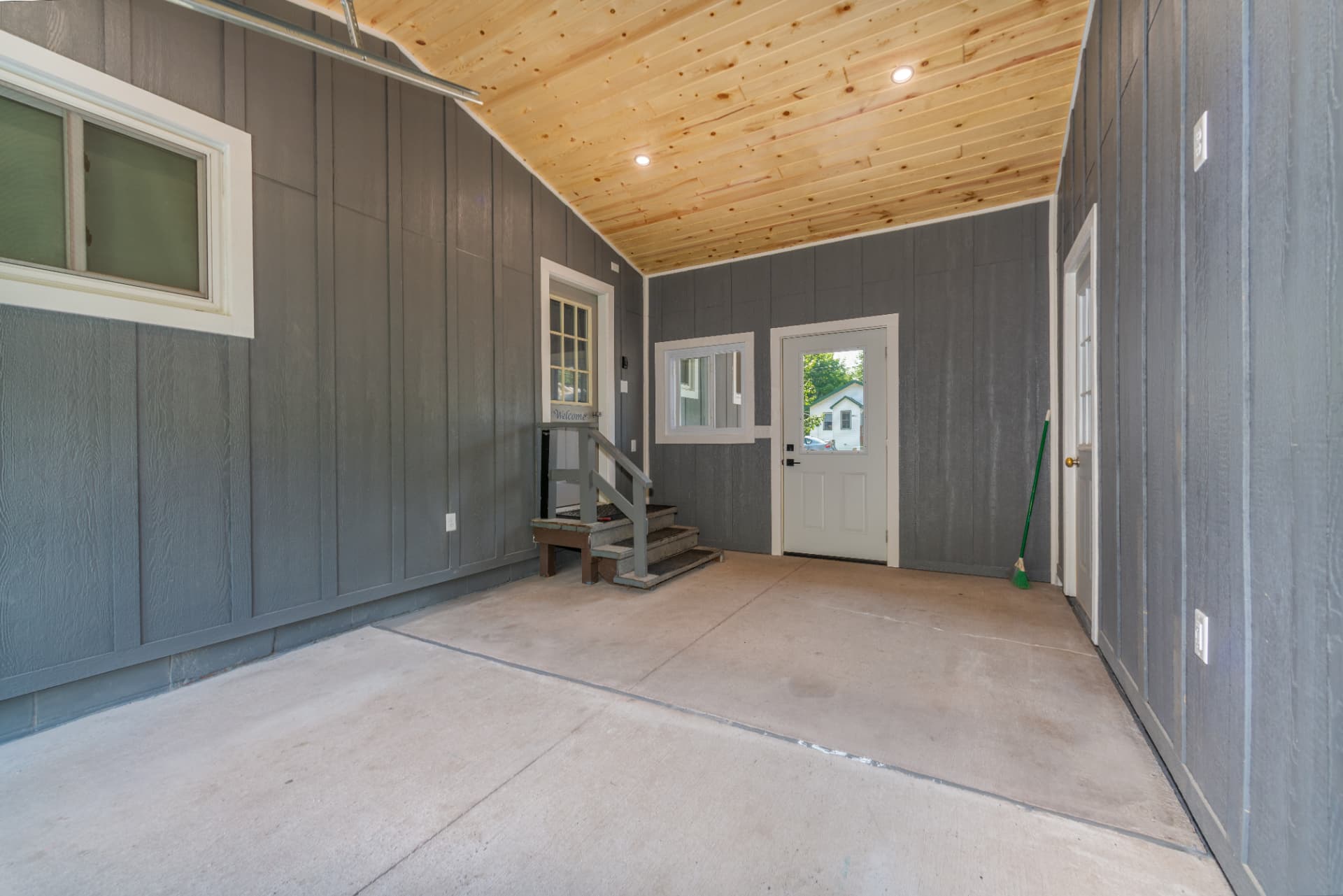 Breezeway interior looking toward the house with cedar T&G ceiling and gray board and batten siding in Marquette County