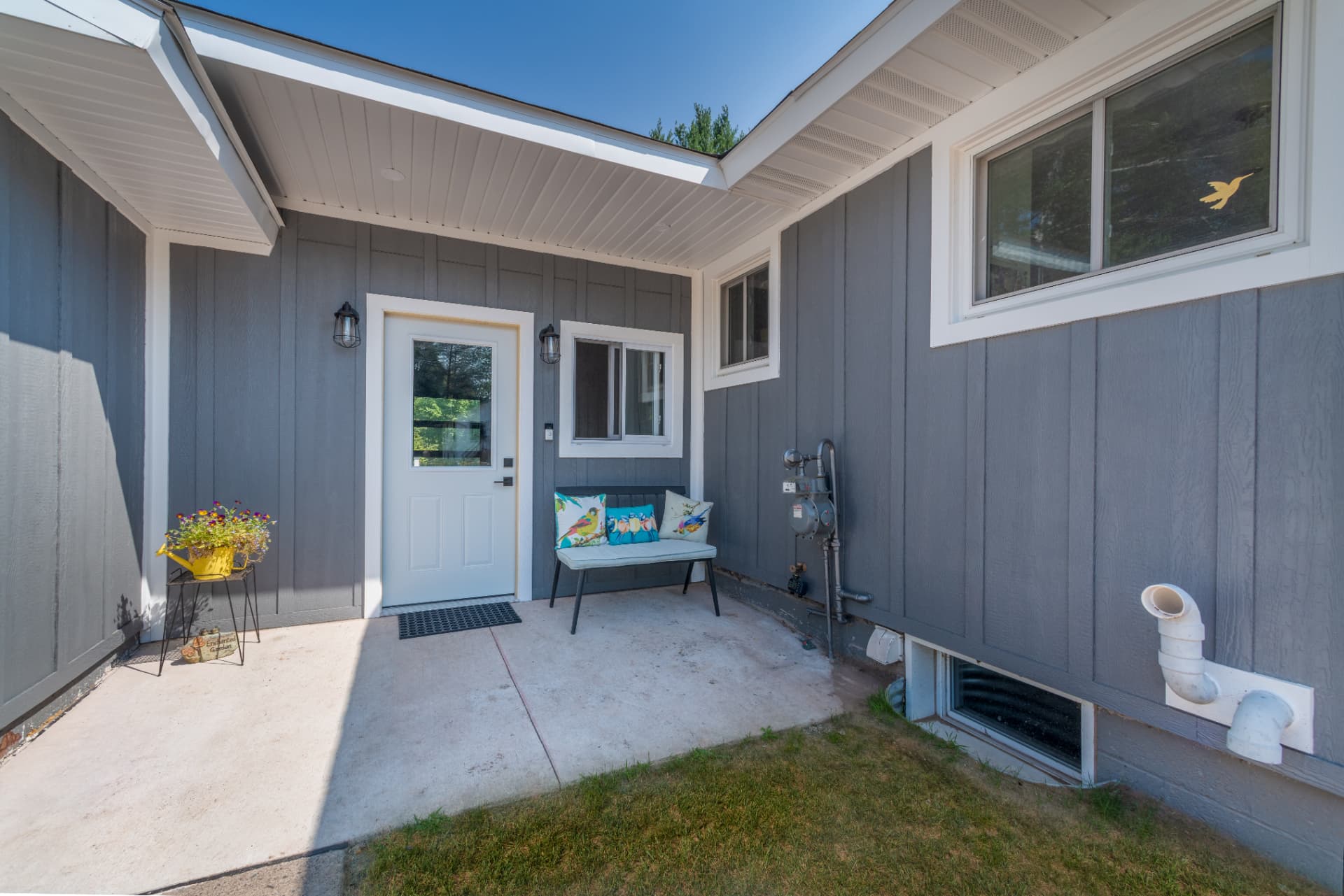 Exterior side view of the house with gray board and batten siding and white entry door in Marquette, MI