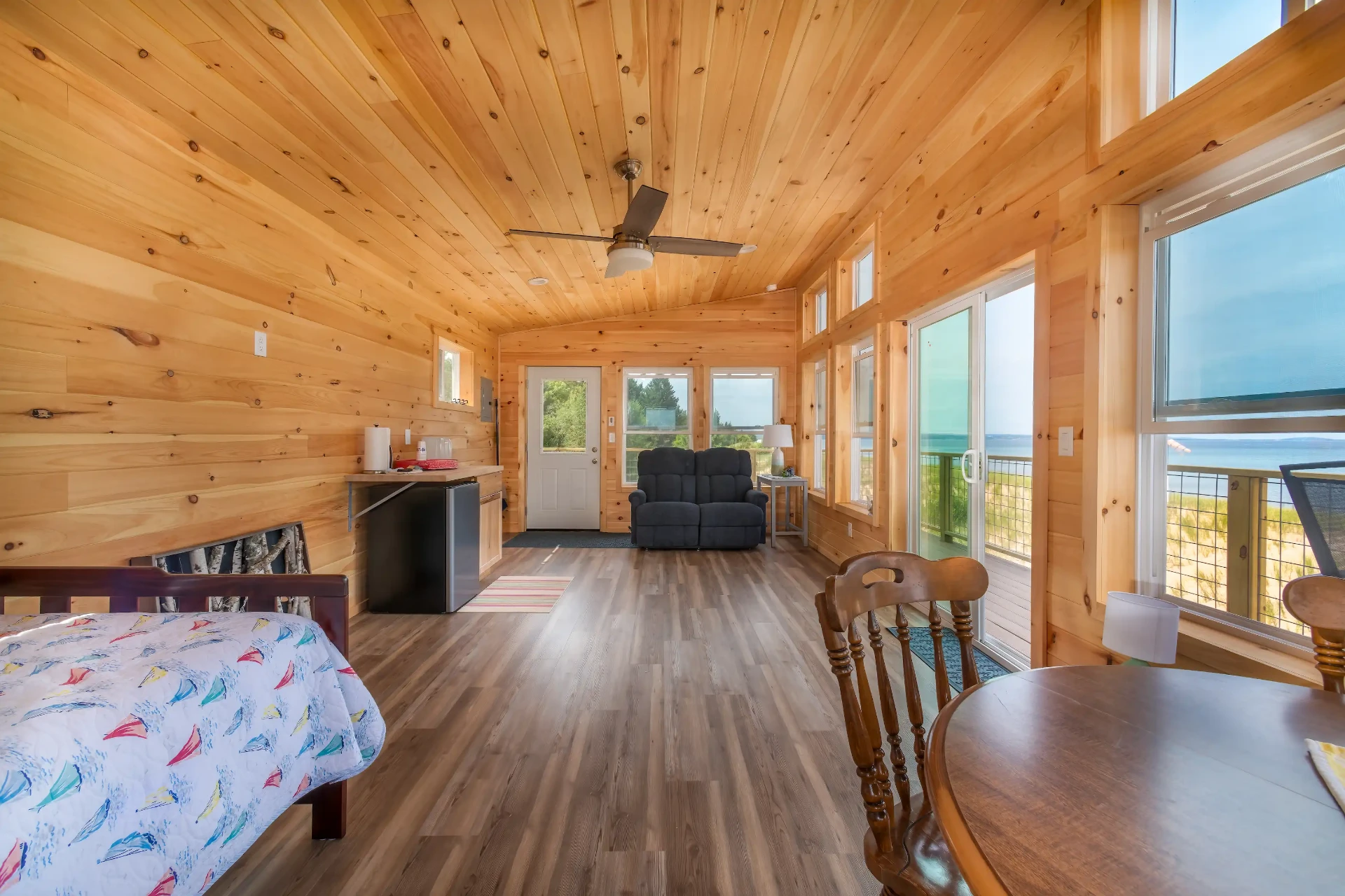Finished knotty pine accessory building interior with hardwood floors, large windows, and Lake Superior views in Marquette County, Michigan